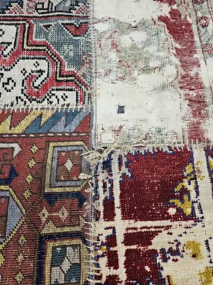 Close view of an antique rug with several worn fragments joined together