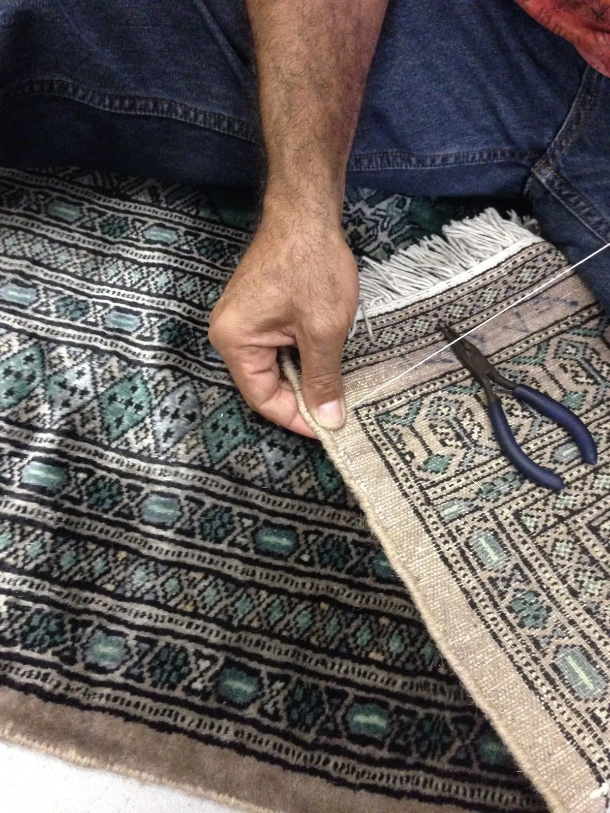 Craftsman working on rug fringe by hand